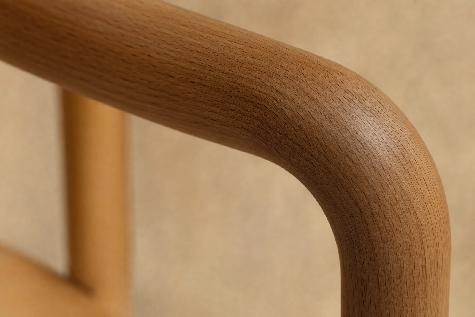 Primo piano di un bracciolo in faggio massello curvato, con la venatura a poro aperto in evidenza